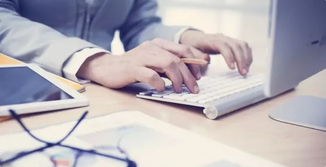 Person in a suit typing at a desk