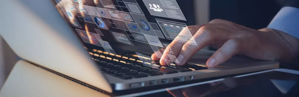 Person in a suit typing at a desk with icons floating above the keyboard outside of the screen